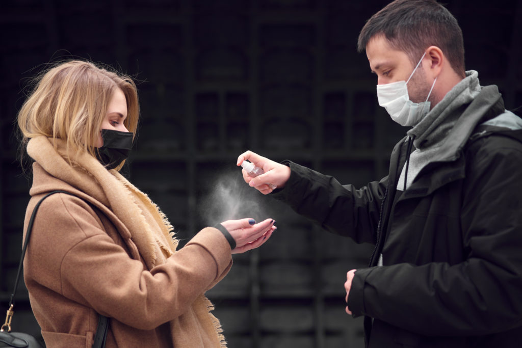 couple using spray sanitzer in public during the covid-19 pandemic 